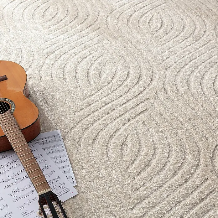 Dekoria Flachgewebeteppich - creme - Nahaufnahme eines beigen Teppichs mit abstraktem Muster, einer Gitarre und Notenblättern, die eine musikalische und dekorative Atmosphäre schaffen.
