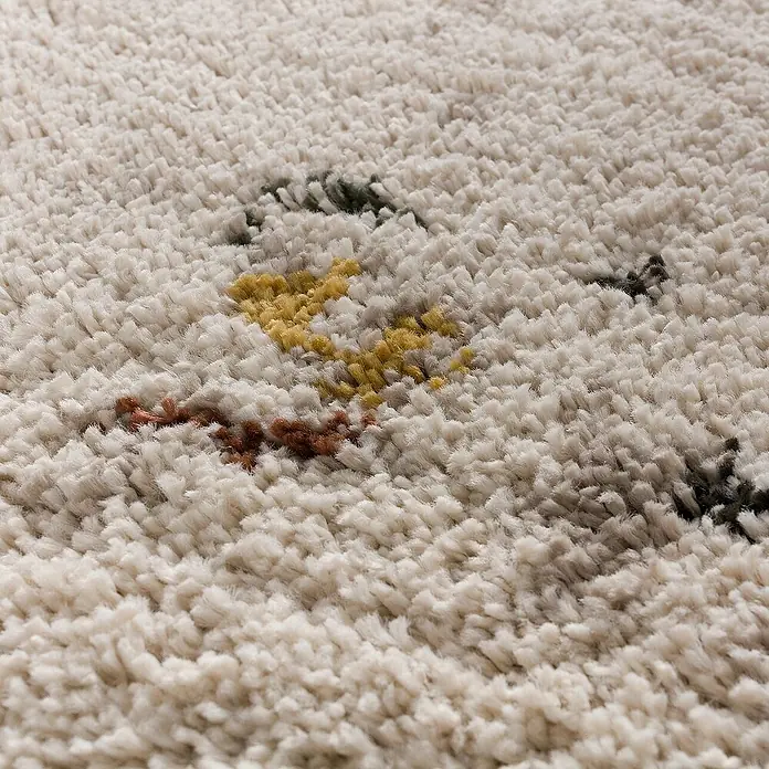 Dekoria Flachgewebeteppich - beige, bunt - Nahaufnahme eines beigefarbenen Teppichs mit farbigen Akzenten, die eine gemütliche Textur und ein warmes Ambiente vermitteln.