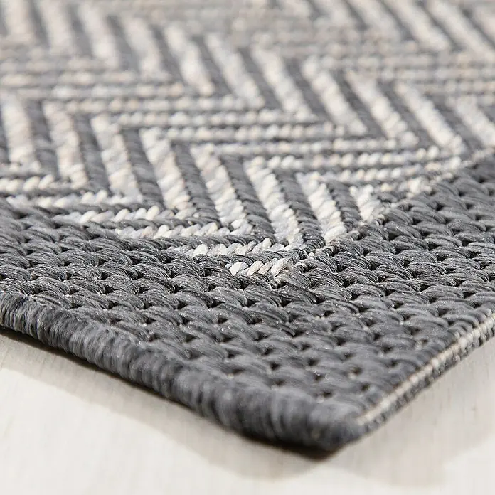 Dekoria Flachgewebeteppich - grau, 170 x 120 cm - Nahaufnahme eines grauen Teppichs mit einem Chevron-Muster. Der Teppich hat eine gewebte Textur und liegt auf einem hellen Holzboden.