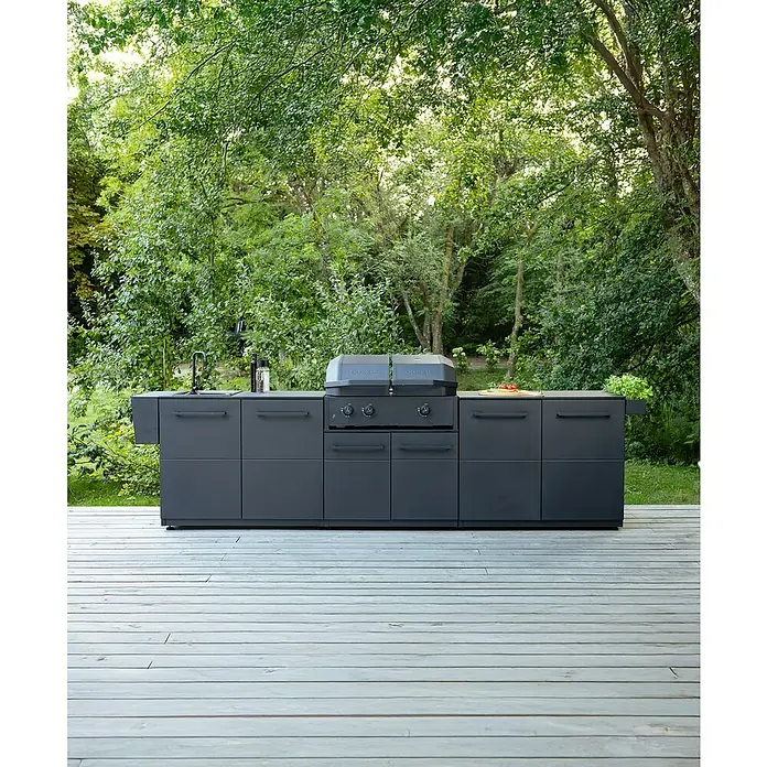 Cozze Elements Outdoorküchen-Modul Spüle - Schwarz, B x T x H: 110 x 60 x 88,5 cm, Stahl - Moderner grauer Außenküchengrill mit Spüle und Arbeitsflächen, eingebettet in eine grüne Gartenszene auf einer Holzterrasse.