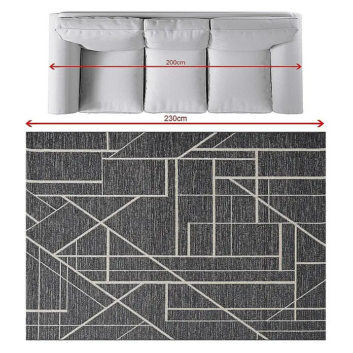 Dekoria Flachgewebeteppich - schwarz, 230 x 160 cm - Sofa und gemusterter Teppich. Das Sofa ist hellgrau und der Teppich hat ein geometrisches Muster in Grau und Weiß.
