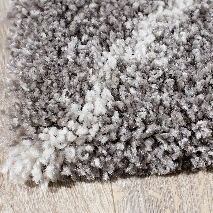 Dekoria Flachgewebeteppich - grau, 290 x 200 cm - Nahaufnahme eines grauen und weißen Shaggy-Teppichs mit weicher Textur, der auf einem Holzboden liegt.