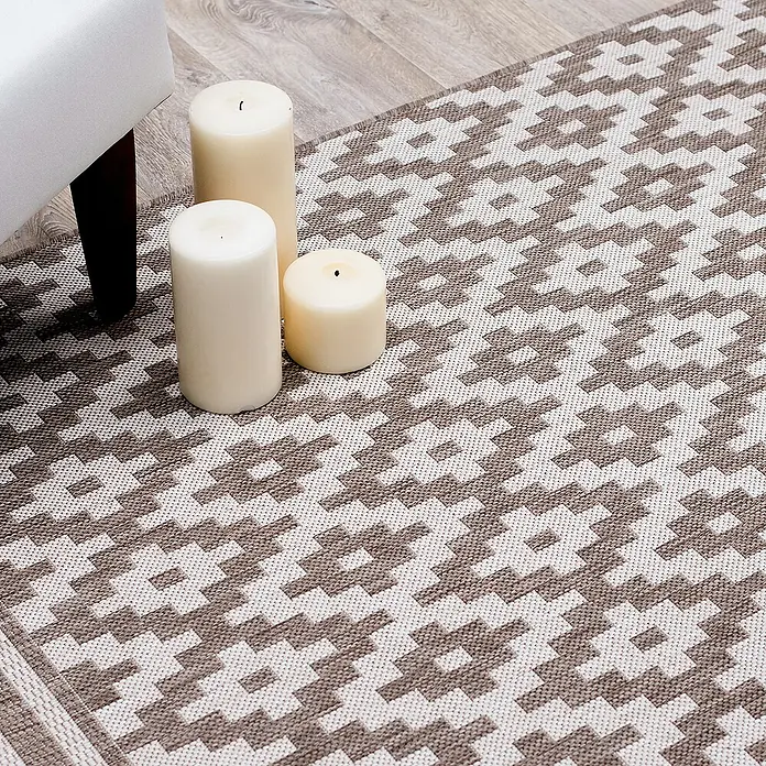 Dekoria Flachgewebeteppich - creme, beige, braun, 230 x 160 cm - Detailaufnahme eines gemusterten Teppichs mit cremefarbenen Kerzen und einem Möbelstück.
