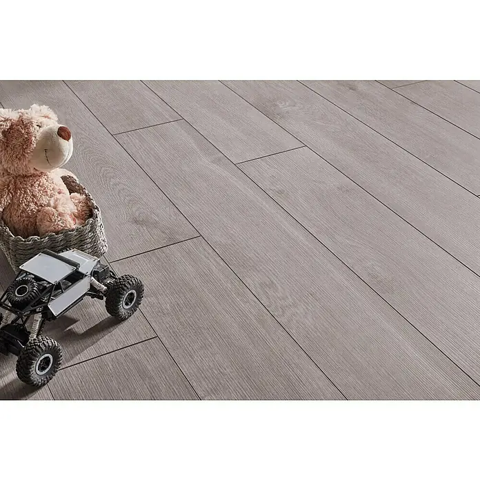 LOGOCLIC Aquaprotect Laminat - Moonlight Oak, Landhausdiele, 1.288 x 195 x 8 mm - Nahaufnahme von einem hellgrauen Holzboden, mit Spielzeug darauf, der die Textur und das Muster des Bodens hervorhebt.