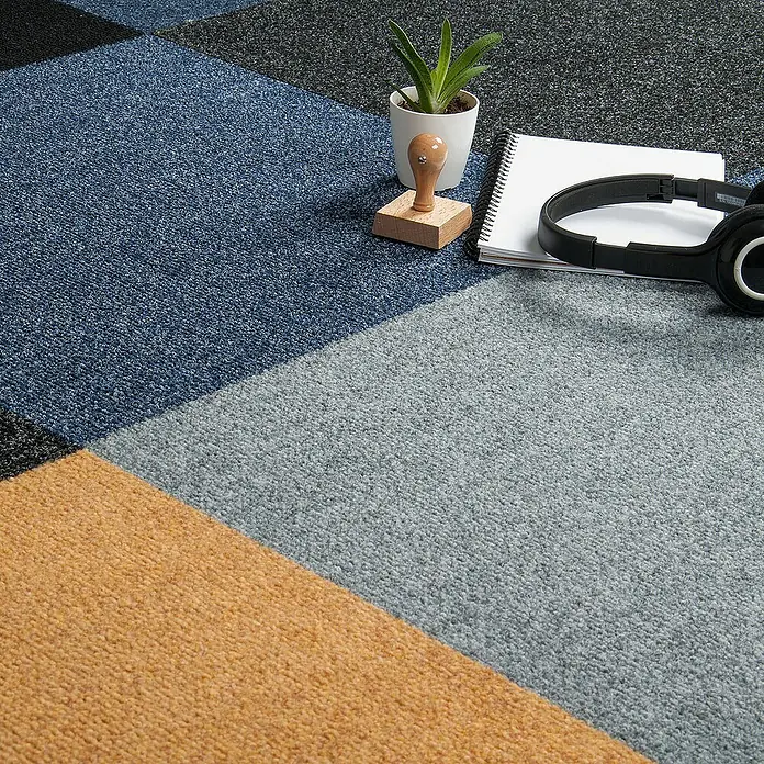 Bricoflor Teppichfliese - Breite: 50 cm, Nadelfilz, Polypropylen, grau - Nahaufnahme der Teppichfliesen in verschiedenen Farben, mit Schreibtischutensilien wie Kopfhörern und einer Pflanze.