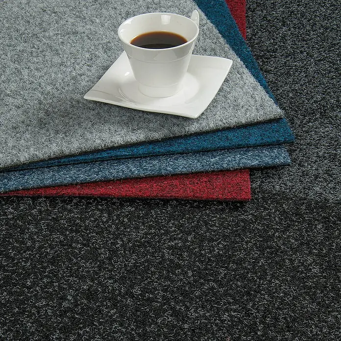Bricoflor Teppichfliese - Breite: 50 cm, Nadelfilz, Polypropylen, rot - Eine Tasse Kaffee auf einem Stapel bunter Teppichfliesen, die eine stilvolle und praktische Bodenlösung darstellen.