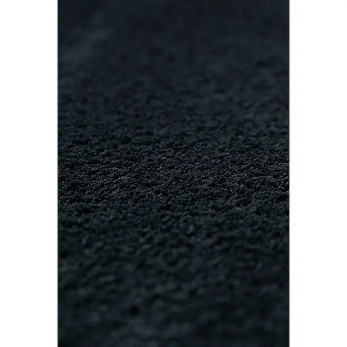 Bricoflor Teppichfliese - Breite: 50 cm, Velours, grau - Nahaufnahme einer strukturierten, dunklen Oberfläche, die an Asphalt oder grobkörniges Material erinnert. Die Textur ist rau und ungleichmäßig.