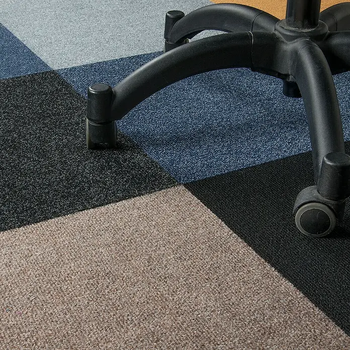 Bricoflor Teppichfliese - Breite: 50 cm, Nadelfilz, Polypropylen, schwarz - Nahaufnahme eines Bürostuhls auf einem Teppich mit farbigen Quadraten, der ein modernes und stilvolles Arbeitsumfeld zeigt.