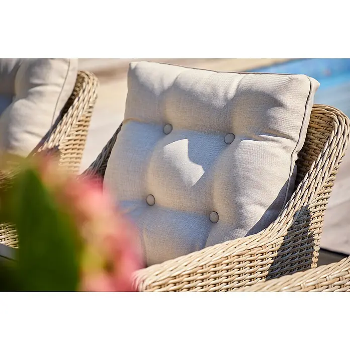Sunfun Gartenmöbel-Set - 7 -tlg., Akazie, Polyrattan, Beige/Braun, Tischplatte erweiterbar - Nahaufnahme eines Rattansessels mit einem hellen, gesteppten Sitzkissen mit Knöpfen, der Komfort und Stil für den Außenbereich verspricht.