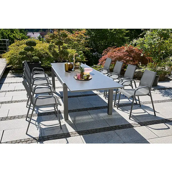 Sunfun Gartenmöbel-Set Maja Stone/Gastro - 9 -tlg., Aluminium, Stahl, Naturstein, Textilen, Night-Grey, Anthrazit - Ein grauer Esstisch mit mehreren Stühlen im Freien, umgeben von üppigem Grün. Perfekt für Mahlzeiten im Freien.