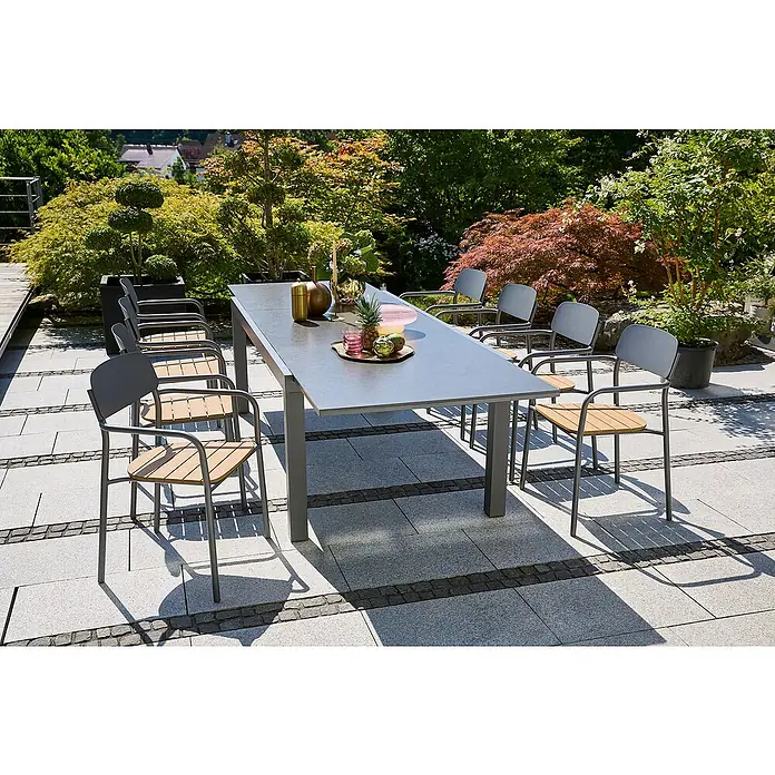 Sunfun Gartenmöbel-Set Maja Stone/Gastro - 9 -tlg., Aluminium, Stahl, Polywood, Naturstein, Night-Grey, Anthrazit - Ein grauer Esstisch mit Metallgestell und Holzstühlen auf einer Terrasse. Die Garnitur wird durch Pflanzen und Dekoration ergänzt.