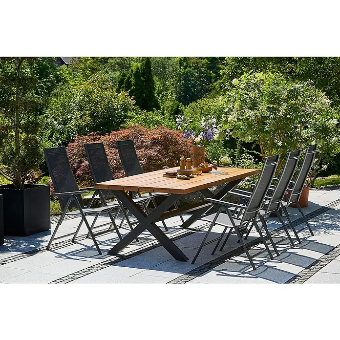 Sunfun Maja Slim Garten-Positionssessel - Aluminium/Textilene, Rückenlehne verstellbar, Anthrazit, B x T x H: 67 x 58 x 110 cm - Ein Gartentisch mit Holzplatte und sechs Stühlen auf einer Terrasse. Das Set steht im Freien, umgeben von üppigem Grün.