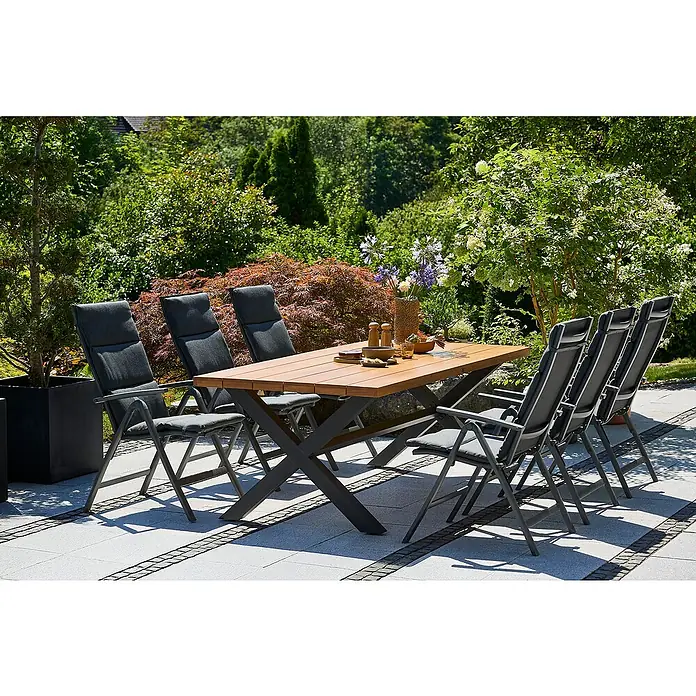 Sunfun Gartenmöbel-Set Maja Slim - 13 -tlg., Eschenholz, Aluminium, Textilen, Olefin, Naturbraun/Night-Grey - Außenaufnahme eines Gartentisches mit Stühlen auf einer Terrasse, umgeben von üppigem Grün. Ideal für Mahlzeiten im Freien.