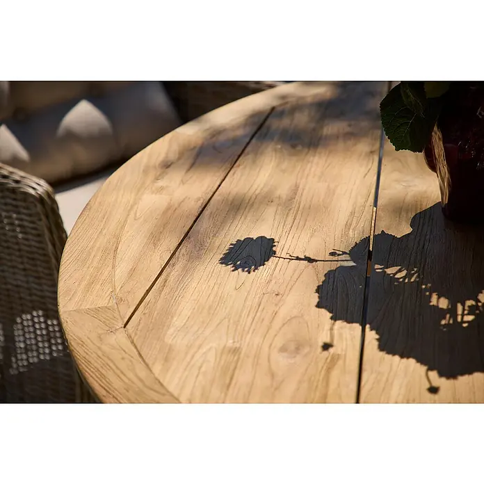 Sunfun Garten-Tischplatte - Durchmesser: 150 cm, Teak, Natur - Nahaufnahme eines runden Holztisches im Freien mit Schatten von Blättern, der die natürliche Holzstruktur hervorhebt.\n