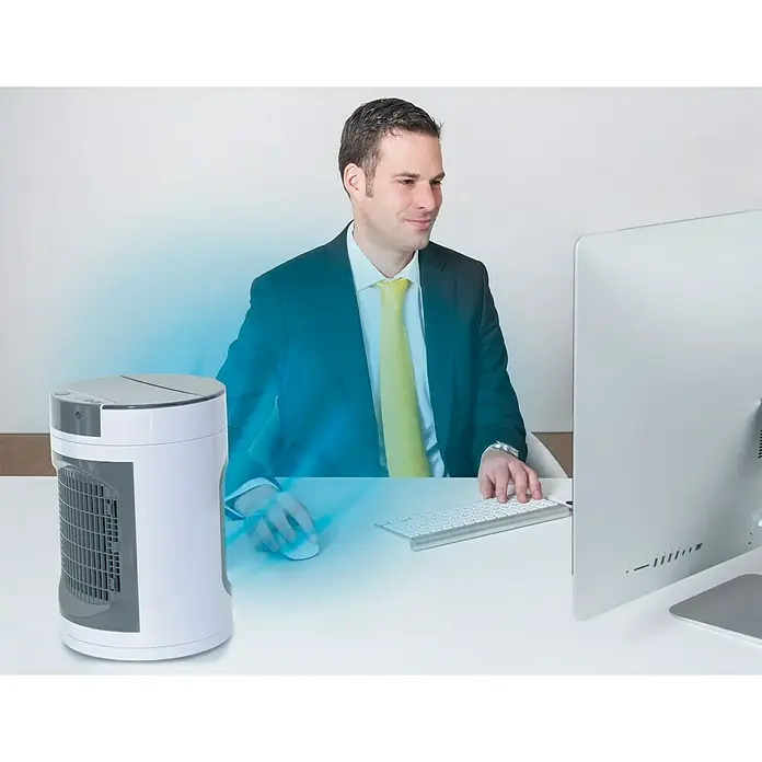 Climatizador evaporativo Smart Chill - 12 W, Blanco, 39,5 cm - Un mini enfriador de aire acondicionado portátil sobre un escritorio, junto a un hombre en traje trabajando en un ordenador.