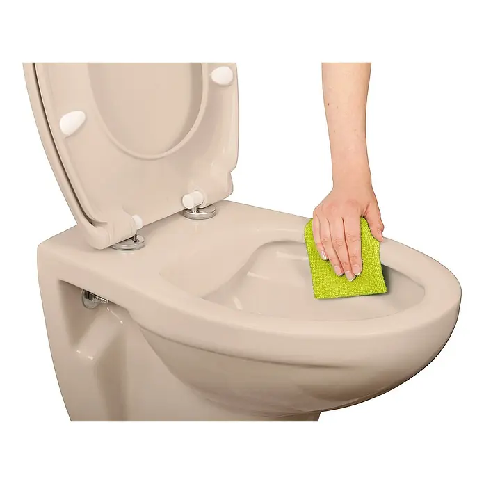 Calmwaters Wand-WC Spülrandlos - Spülrandlos, Ohne Spezialglasur, Spülform: Tief, WC Abgang: Waagerecht, Bahamabeige - Eine Hand wischt eine beigefarbene Toilette mit einem grünen Tuch ab. Die Toilette steht vor einem weißen Hintergrund und der Toilettendeckel ist offen.