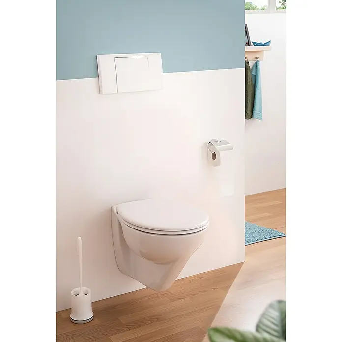 Calmwaters Wand-WC-Set Spülrandlos mit Erhöhung - Spülrandlos, Ohne Spezialglasur, Spülform: Tief, WC Abgang: Waagerecht, Weiß - Eine moderne, wandhängende Toilette mit Betätigungsplatte und Toilettenpapierhalter in einem stilvollen Badezimmer.