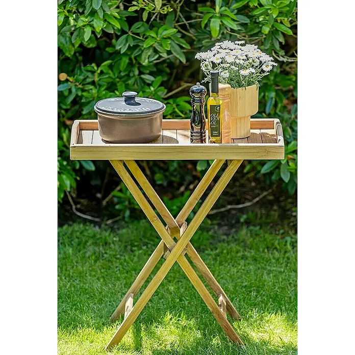 Kai Wiechmann Garten-Beistelltisch - L x B x H: 70 x 35 x 74 cm, Teakholz, Klappbar, Rechteckig, Naturbelassen - Gartentisch mit Speisen und Getränken. Ein hübscher Tisch mit Topf, Blumen, Pfeffermühle und Ölflaschen auf dem Rasen im Garten.