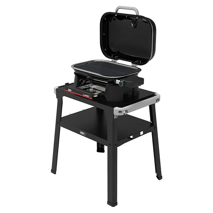 Weber Compact Elektrogrill Lumin Compact mit Grilltisch - Grillfläche (B x T): 43 x 28 cm, 2,2 kW - Das Bild zeigt einen Weber Lumin Elektrogrill auf einem schwarzen Untergestell, ideal für Balkone und kleine Terrassen. Er hat einen offenen Deckel und ein modernes Design.