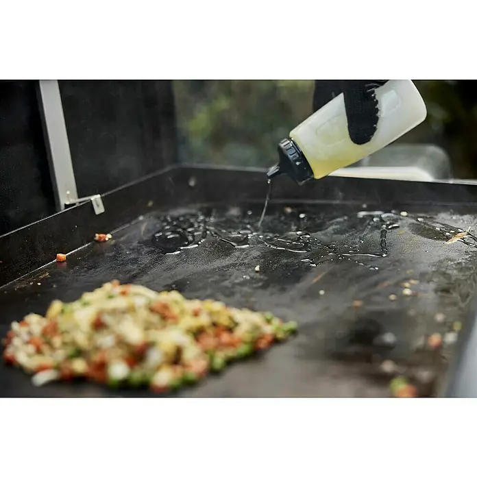 Weber Quetschflasche - 473 ml, Kunststoff, 2 -tlg. - Öl wird auf eine Grillplatte gegossen, um mit dem Kochen von Reis zu beginnen.