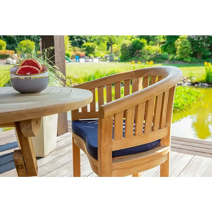 Kai Wiechmann Sitzauflage - Sessel, Polyacryl, Anthrazit - Nahaufnahme eines Teakholzstuhls mit blauer Polsterung und einem runden Teakholztisch mit Obstschale im Garten.