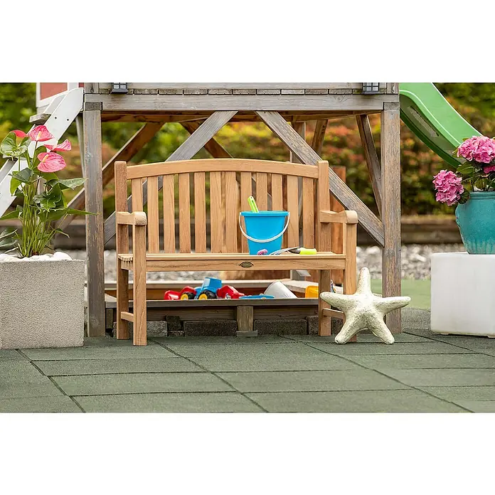 Kai Wiechmann Kinder-Gartenstuhl - Teakholz, Naturbelassen, B x T x H: 80 x 44 x 66 cm - Eine charmante Szene mit einer hölzernen Gartenbank, dekoriert mit einem blauen Eimer und Spielzeug, unter einem Spielhaus platziert.