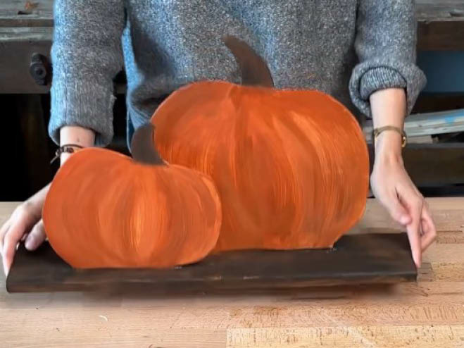 Die fertige Herbstdeko mit angemalten Kürbissen aus Holz wird präsentiert