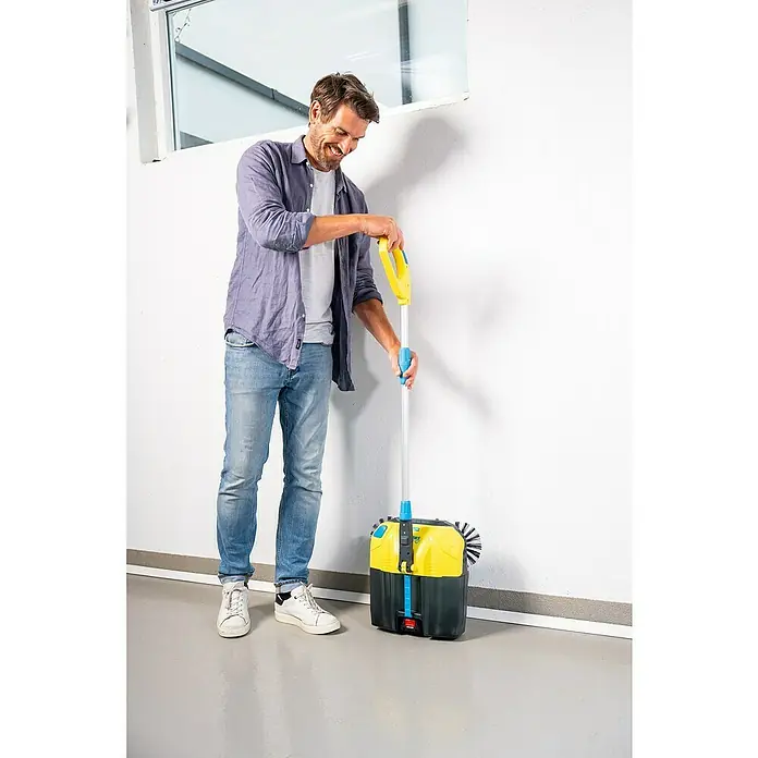 Gloria Power for All 18V Akku-Handkehrmaschine EasySweep 18V - 18 V, 1 Akku, Arbeitsbreite: 40 cm, 4,5 l - Mann mit Akku-Kehrmaschine. Die Akku-Kehrmaschine ist gelb und schwarz und hat einen Griff zum Schieben. Der Mann lächelt.