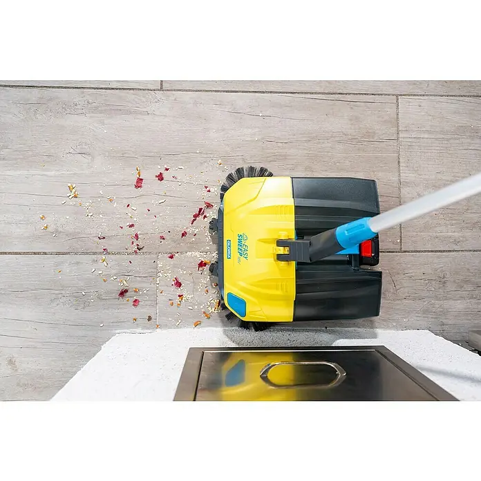 Gloria Power for All 18V Akku-Handkehrmaschine EasySweep 18V - 18 V, 1 Akku, Arbeitsbreite: 40 cm, 4,5 l - Ein gelber Gloria Akku-Besen reinigt einen Holzboden von kleinen Krümeln und anderem Schmutz.