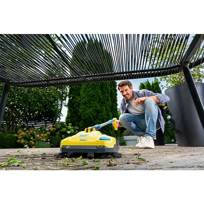 Gloria Power for All 18V Akku-Handkehrmaschine EasySweep 18V - 18 V, 1 Akku, Arbeitsbreite: 40 cm, 4,5 l - Ein Mann benutzt eine Gloria EasySweep 18V Kehrmaschine auf einer Holzterrasse, um Blätter und Schmutz zu entfernen. Die Maschine ist gelb und grau.