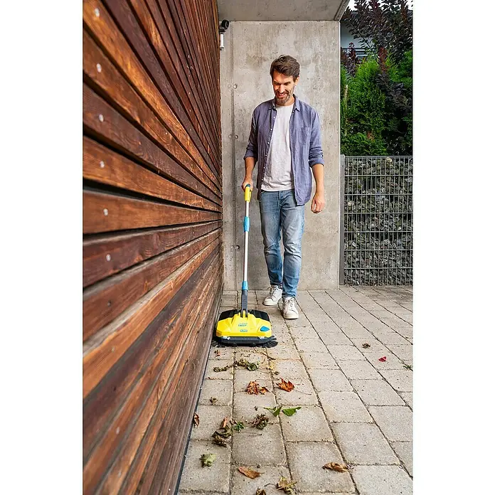 Gloria Power for All 18V Akku-Handkehrmaschine EasySweep 18V - 18 V, Ohne Akku, Arbeitsbreite: 40 cm, 4,5 l - Ein Mann benutzt einen gelben Kehrmaschine draußen, um Blätter zu entfernen. Das Gerät ist ideal zum schnellen Reinigen von Gehwegen und Terrassen.