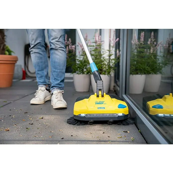 Gloria Power for All 18V Akku-Handkehrmaschine EasySweep 18V - 18 V, Ohne Akku, Arbeitsbreite: 40 cm, 4,5 l - Der Gloria EasySweep 18V Akku-Kehrer in Aktion: Der gelbe Kehrer mit Teleskopstiel reinigt eine Terrasse mit herumliegenden Blättern.