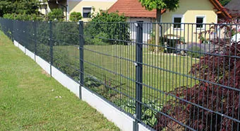 Metallzaun rund um ein Grundstück mit Garten und Haus