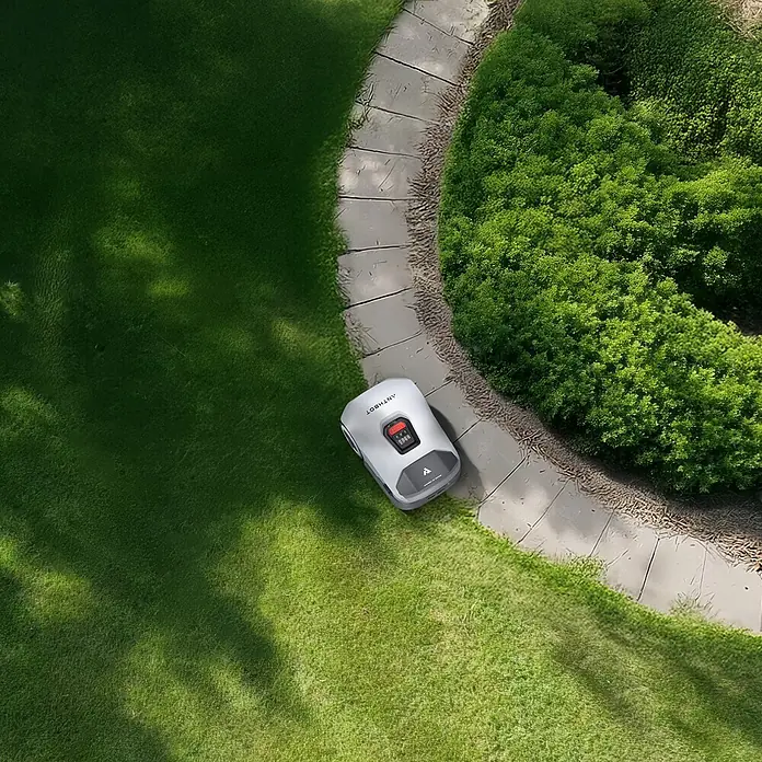 Anthbot Mähroboter Genie 3000 - 3.600 m², Schnittbreite: 20 cm, Satellitengestützte Navigation, RTK - Ein Mähroboter der Marke Antbot mäht präzise den Rasen neben einem gepflasterten Weg und einem Busch.