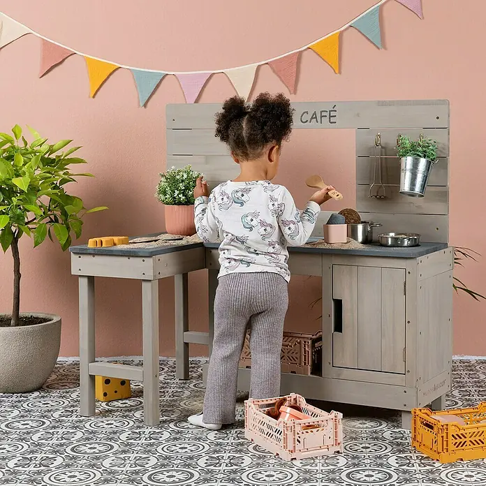 Muddy Buddy Matschküche Coffee Corner - 100 x 60 x 95 cm, Holz, Warmgrau - Kind spielt mit einer robusten Spielküche aus Holz in Grau, die zum fantasievollen Kochen und Café-Spielen einlädt.