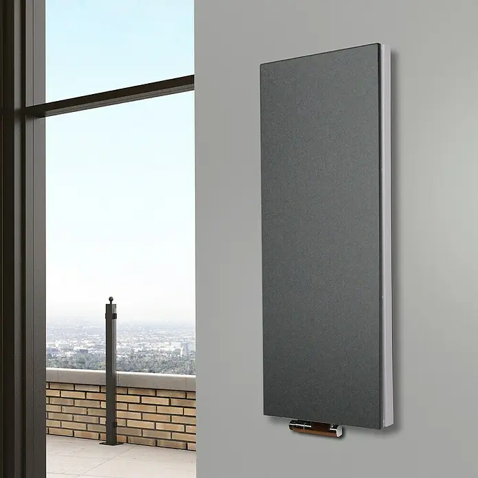 Badheizkörper Manhattan - B x H: 470 x 1.200 mm, Moonstone, Ohne Handtuchhalter, Nennleistung: 1.458 W - Vertikaler Heizkörper in stilvollem Grau, montiert an einer grauen Wand, mit Blick auf eine Stadtlandschaft im Hintergrund.