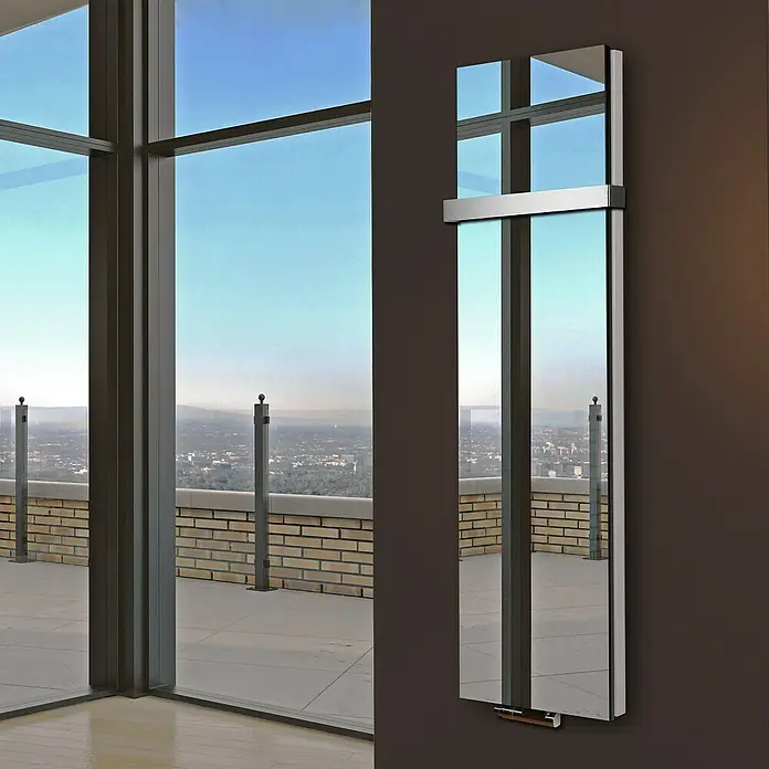 Badheizkörper Mirror - B x H: 470 x 1.800 mm, Nennleistung: 1.964 W, 1 x Halter 50mm, Spiegel - Ein moderner, vertikaler Spiegelheizkörper an einer Wand mit Fenster im Hintergrund. Sein schlankes Design ergänzt das luxuriöse Ambiente.