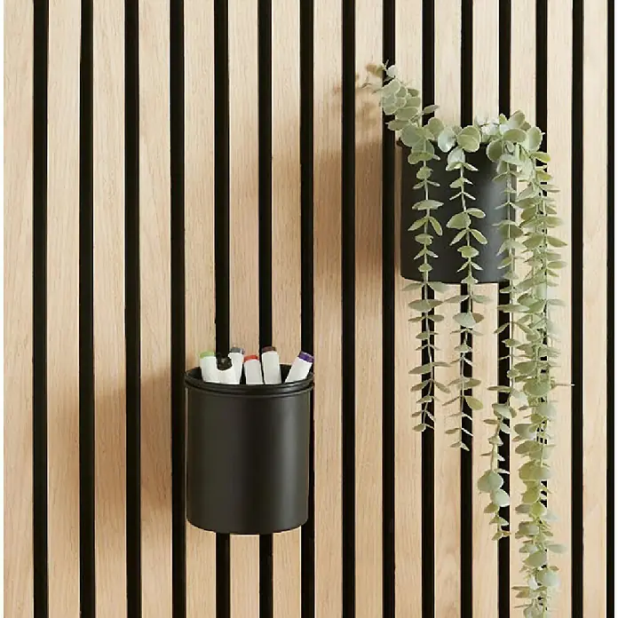 Millex Wandhalterung - Ø x H: 10,5 x 12 cm, Passend für: Akustikpaneele, Montageart: Einhängen - Wandpaneel mit schwarzem Stifthalter mit Stiften und einer Pflanze in einem Topf. Die Lamellen sind hellbraun und schwarz.