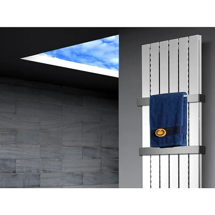 Badheizkörper Peking - B x H: 470 x 1.800 mm, Nennleistung: 1.964 W, Weiß, 2 x Halter 50mm - Ein schlanker, silberner Handtuchwärmer mit einem blauen Handtuch, das mit einem goldenen Emblem verziert ist, montiert an einer grauen Wand.