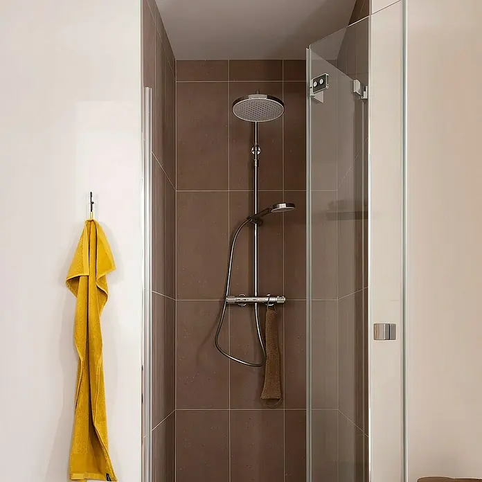 SCHÖNER WOHNEN-Kollektion Duschsystem Glaia mit Thermostat Wassersparend Chrom - Anzahl Strahlarten: 3 Stk., Chrom - Duschkabine mit Regendusche und Handbrause. Ein gelbes Handtuch hängt an der Wand, während ein braunes Handtuch in der Dusche hängt.