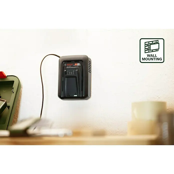 Bosch Power for All 18V Akku & Ladegerät Starter-Set - 1 x 18V/2,5 Akku, 1 x Ladegerät AL 18V-44 - Nahaufnahme eines Bosch Akku-Ladegeräts AL 18V-4A, das an einer Wand befestigt ist und ein grünes Licht anzeigt, mit einem Kabelanschluss.
