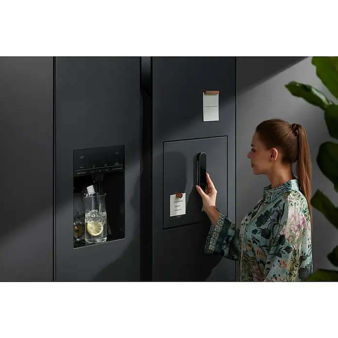 Typhur Einstichthermometer InstaProbe Core - Messbereich: -49,9°C-299,9°C - Eine Frau interagiert mit einem modernen, schwarzen Kühlschrank mit Wasserspender und Notizen, der Stil und Funktionalität vereint.