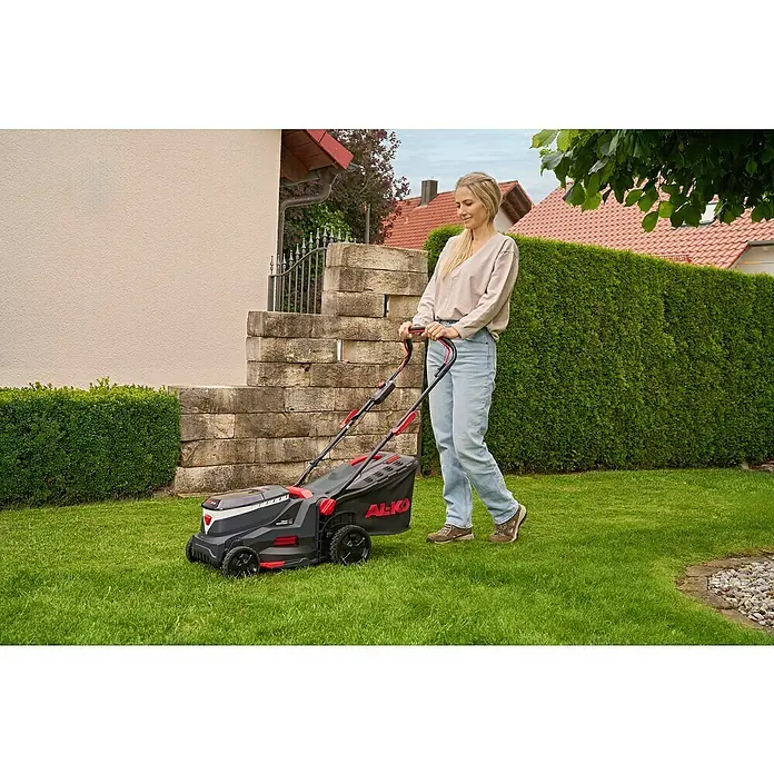 AL-KO 18V/36V Akku-Rasenmäher 34.6 - 18 V - 36 V, 2 Akkus, 2,5 Ah, Schnittbreite: 34 cm - Frau mäht Rasen mit einem AL-KO Akku-Rasenmäher. Der Rasenmäher ist schwarz und rot.