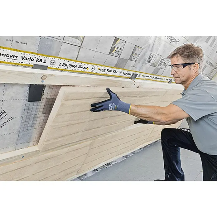 Isover Lanaé Glaswolle Untersparrenfilz WLS 032 - Stärke: 60 mm, Wärmeleitfähigkeit: 0,032 W/(mK) - Ein Handwerker montiert eine Isover Vario KB 1 Dampfbremsfolie an einer Wand. Die Folie bietet optimalen Schutz vor Feuchtigkeit und Schimmel.