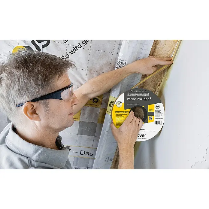 Isover Vario Dichtungsband ProTape+ - L x B: 12,5 m x 12 mm - Handwerker mit Vario ProTape+ beim Verkleben einer Klimamembran. Das Band sorgt für eine einfache und schnelle Abdichtung im Innenausbau.