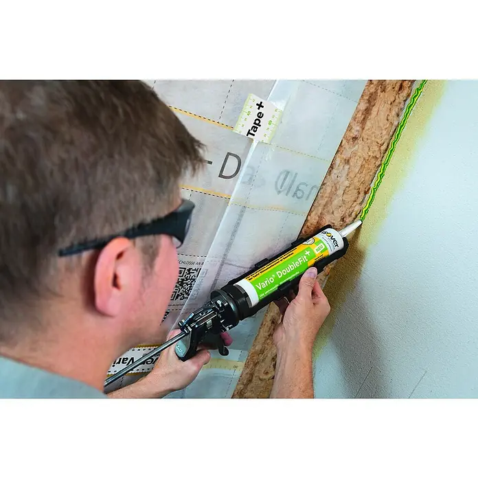 Isover Vario Dichtstoff Doublefit+ - 310 ml - Anwender trägt mit einer Kartuschenpistole Dichtstoff Isover Vario Double Fit+ auf eine Wand auf, um eine luftdichte Abdichtung zu gewährleisten.