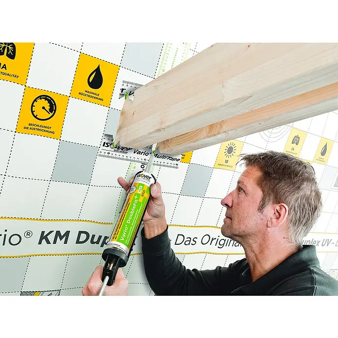 Isover Vario Dichtstoff Doublefit+ - 310 ml - Ein Handwerker verwendet Isover Vario DoubleFit, einen dauerelastischen Klebstoff, um eine Holzkonstruktion an einer Wand zu befestigen.
