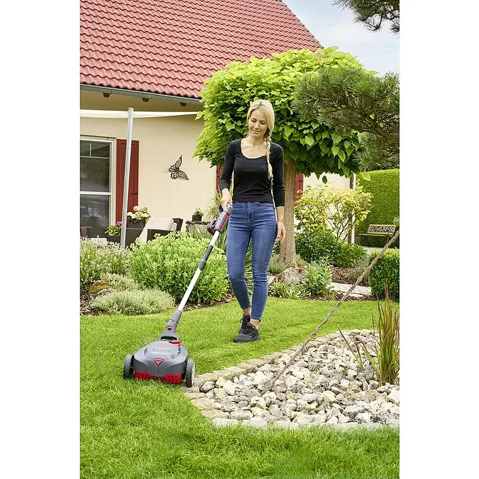 AL-KO 18V/36V Akku-Rasenmäher 22.6 - 18 V - 36 V, 1 Akku, 2,5 Ah, Schnittbreite: 22 cm - Frau benutzt einen Rasenlüfter im Garten. Das Gerät ist grau-rot und hat Räder für eine einfache Handhabung auf dem Rasen.