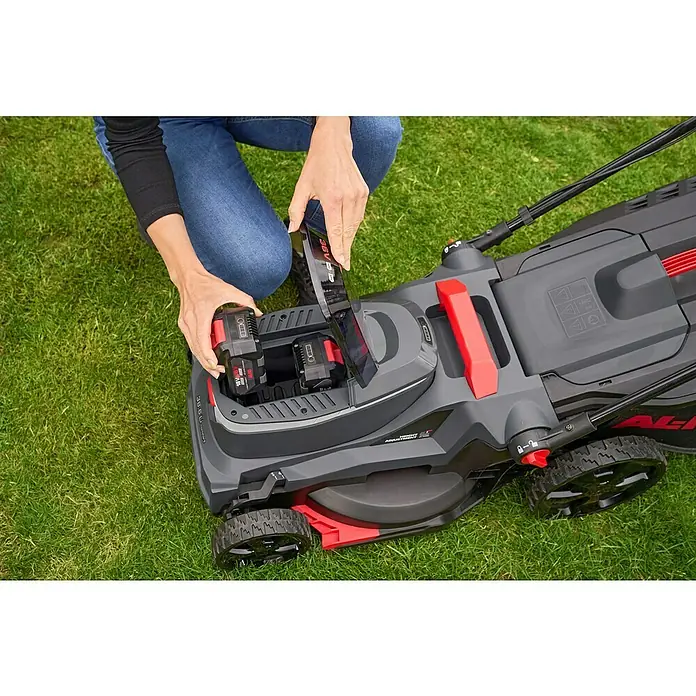 AL-KO 18V/36V Akku-Rasenmäher 38.6 - 18 V - 36 V, 2 Akkus, 4 Ah, Schnittbreite: 38 cm - Eine Person setzt einen Akku in einen AL-KO Rasenmäher ein. Der Rasenmäher ist grau und rot und steht auf einem grünen Rasen.
