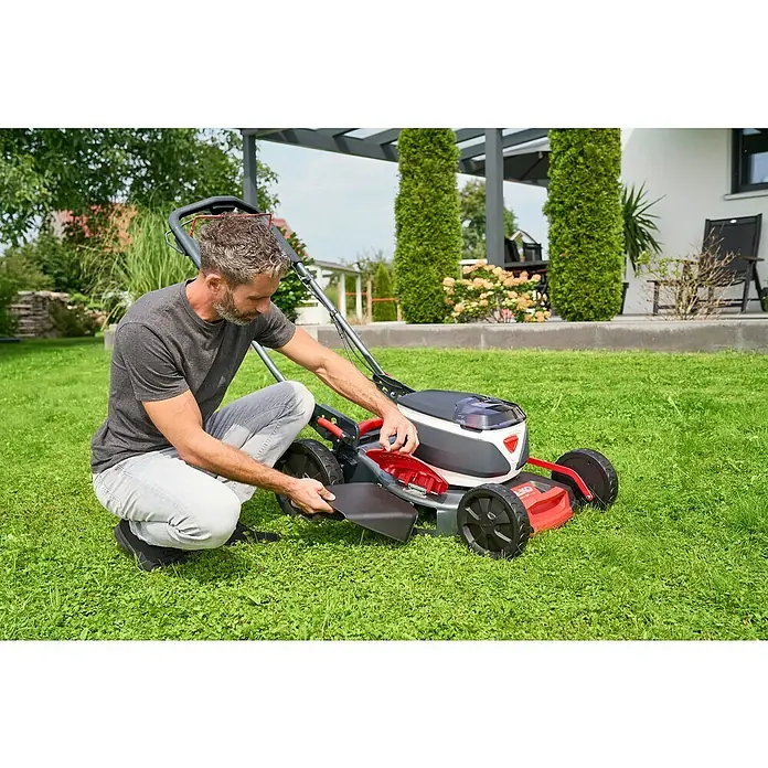 AL-KO 18V/36V Akku-Rasenmäher 46.6 - 18 V - 36 V, 2 Akkus, 5 Ah, Schnittbreite: 46 cm - Mann befestigt den Grasfangkorb an einem AL-KO Akku-Rasenmäher im Garten, bereit für die Gartenarbeit.